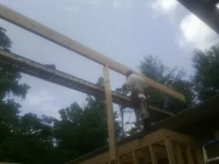 Carpenter setting a ridge beam over a new addition frame — Ice Dam Removal by Roofing Brothers in Spindale