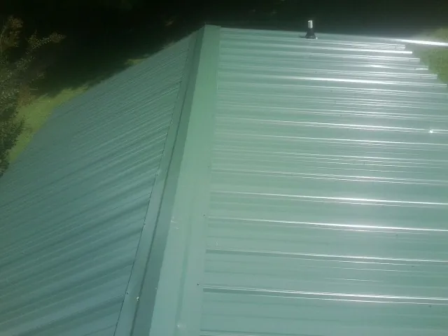 New green metal panels meeting at the ridge of a roof — Flat Roof Repair work by our crew in Spindale