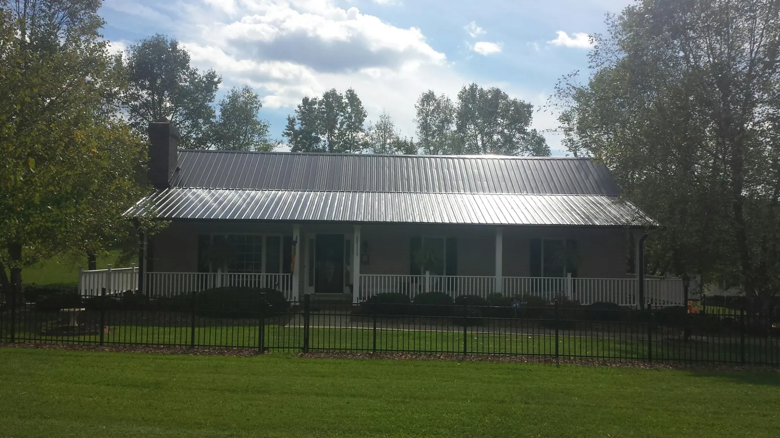 Gray metal roof on a brick ranch with a full width front porch — Gutter Guard Installation work by our crew in Spindale